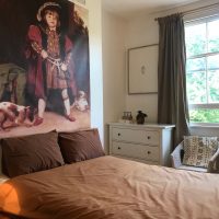 Double bed with brown cover and large picture of child dressed as Henry VIII above