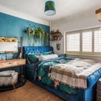 Turquoise blue walls with double bed and colourful rug over bed