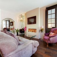 Very smart light-filled room with mauve sofa and dark wooden floor