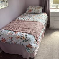 Pink painted walls of single bedroom, with window to side of bed