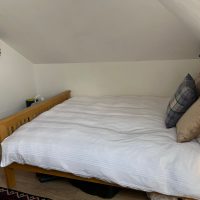 Double bed with duvet and cushions under the eaves