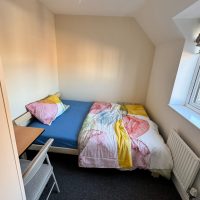 Bright duvet cover on blue sheeted bed with light coming from window