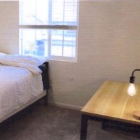 Bed with side table and light near window