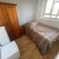 Bed, wardrobe and fridge in bright room