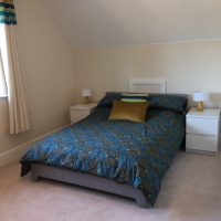 Double bed with dark blue cover in modern light room