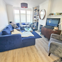 Large blue sofa and arm chair facing tv and fireplace in bright room