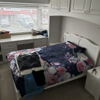 Fitted wardrobes, window with blind and matching bed with bright flowery duvet cover