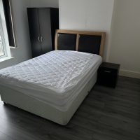 Double bed with dark wood wardrobe and floor. Mattress cover only.