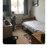 Single bed under window with desk and side table