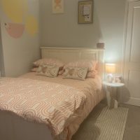 Light grey painted walls, white bedstead and modern style rug and duvet