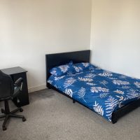 Blue bed covers on bed in flat share in Stratford